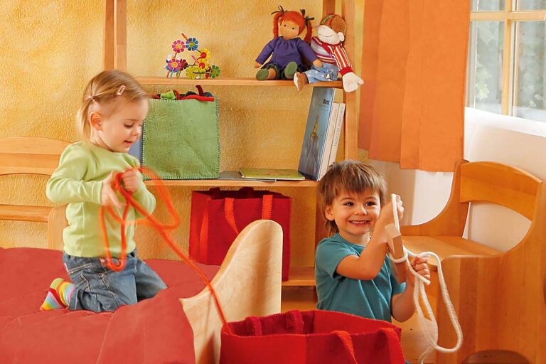 Spielende Kinder in einem gelb-orange gehaltenen Bereich des Kinderzimmers