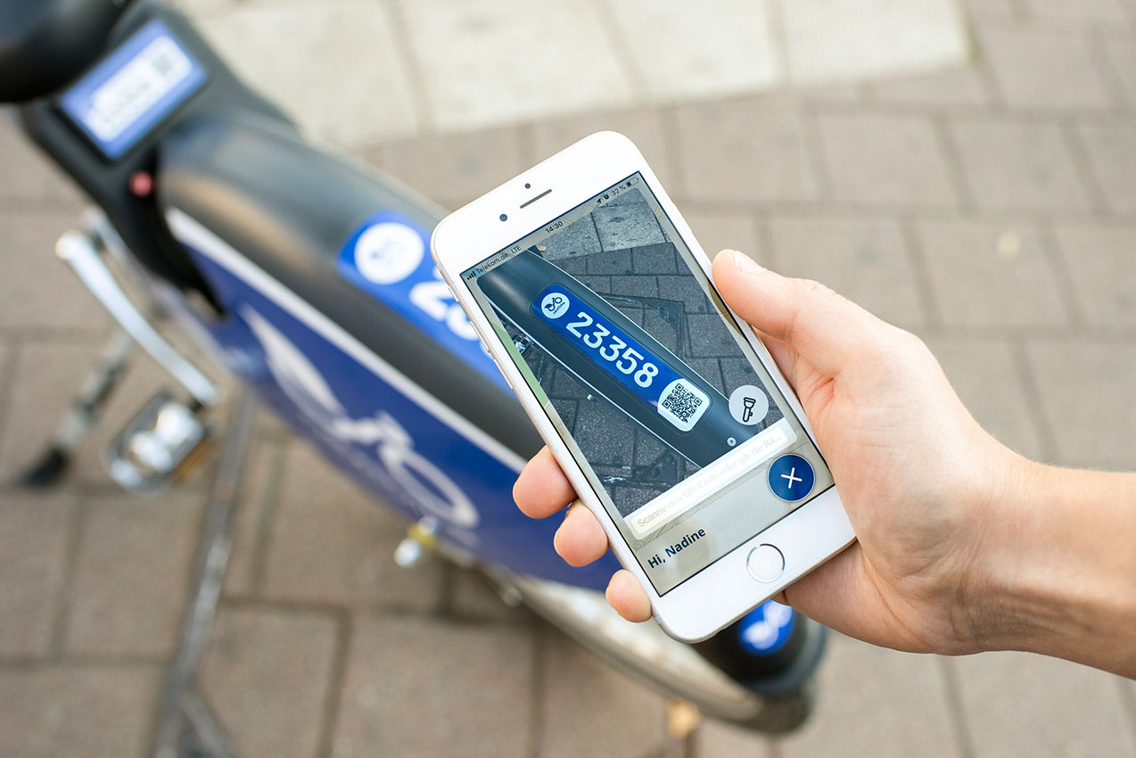 Mit einem Smartphone wird ein QR-Code an einem Leihfahrrad gescannt.