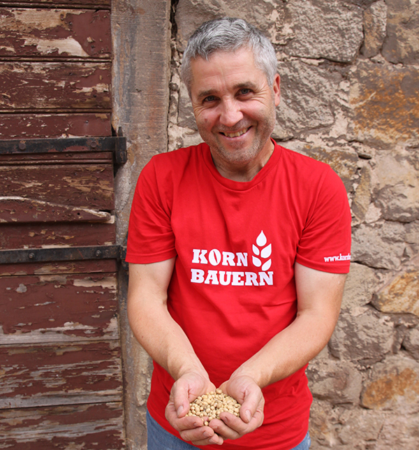 Der kornbauer hält die frisch geernteten Sojabohnen in seinen Händen.