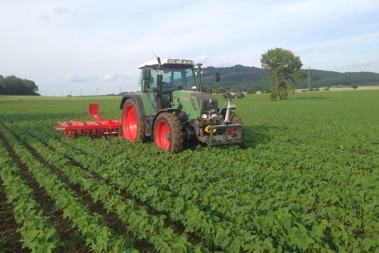 Der Tracktor fährt über ein Sojafeld in Deutschland.