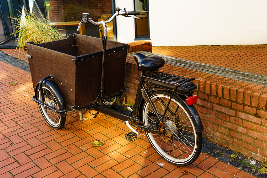 Ein vor dem Hauseingang abgestelltes schwarzes Lastenfahrrad.