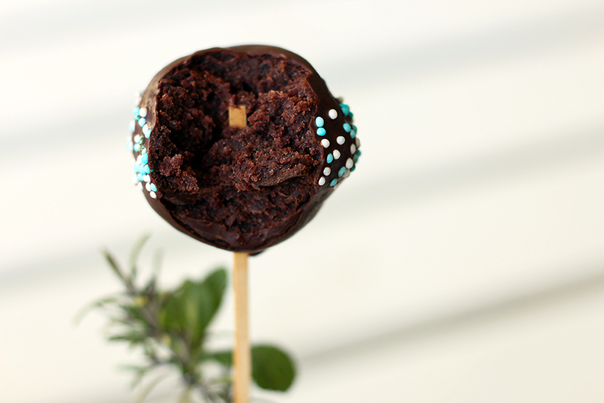 Ein angebissener Cake Pop mit dunklem Teig ist zu sehen.