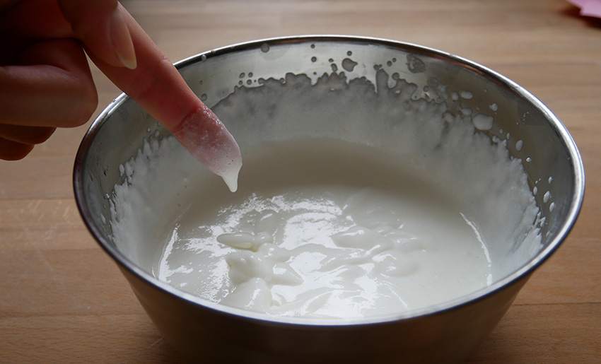 Vom Finger tropft etwas Lotion in die Schüssel.