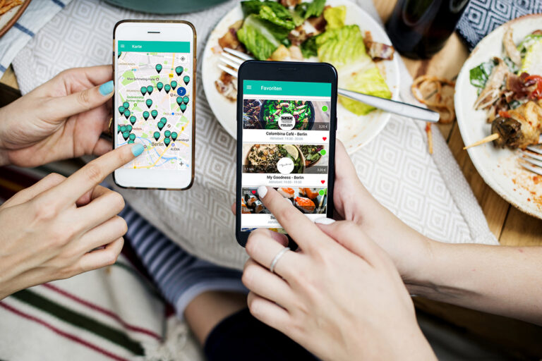 Zwei Smartphone-Displaay zeigen eine Essenretter-App und im Hintergrund sieht man Essen.