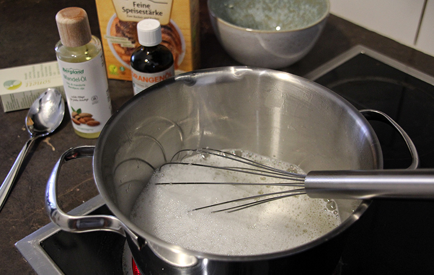 De zelfgemaakte douchegel wordt bereid in een pan op het fornuis, met de ingrediënten aan de linkerkant.