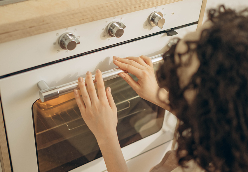 Zum Strom sparen wird der Backofen von einer Frau richtig eingestellt.