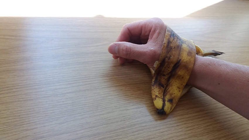 Die Bananenschale ist um eine Hand gelegt.