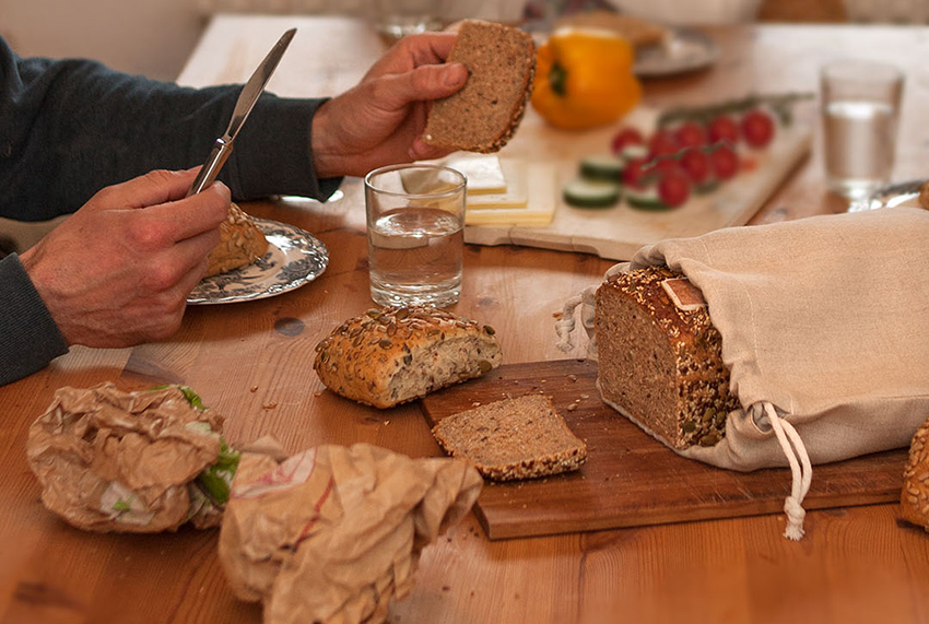 Ein gedeckter Frühstückstisch, auf dem es Brot und Brötchen zur Auswahl gibt.