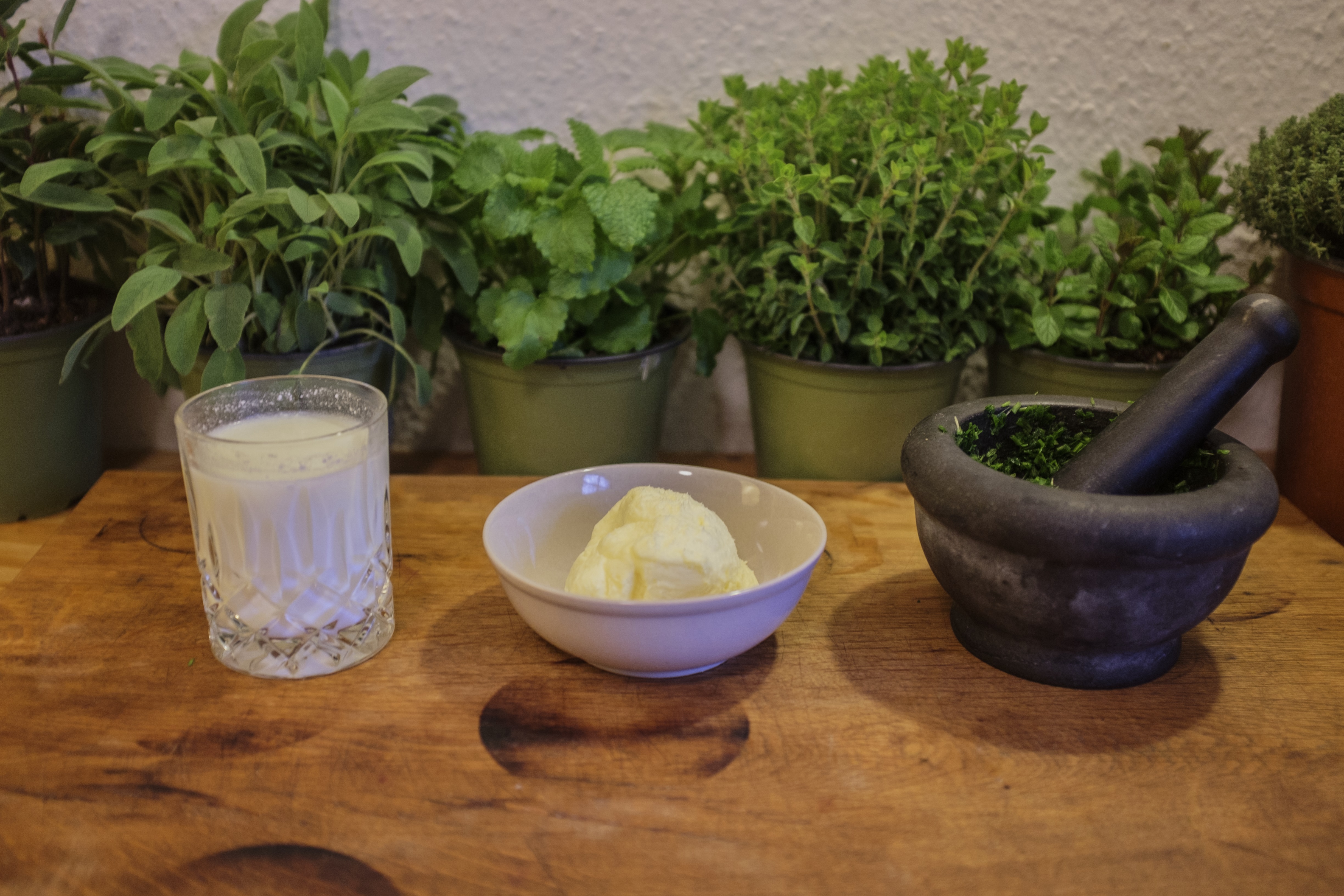 Nach den ersten Arbeitsschritten estehen Butter, Buttermilch und gehackte Kräuter auf dem Tisch