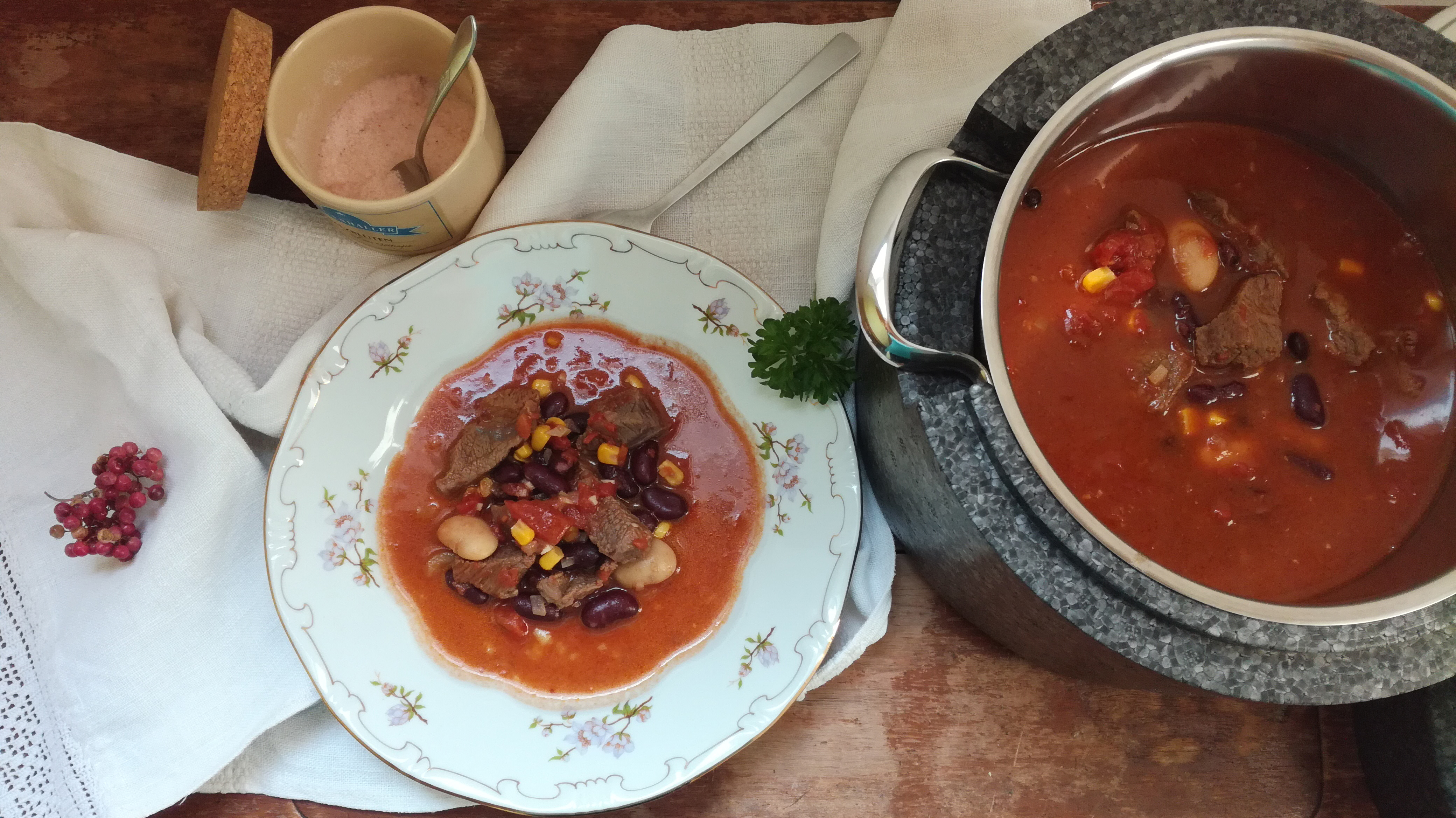 Neben dem geöffneten Thermotopf steht ein gefüllter Teller mit Chili con carne.