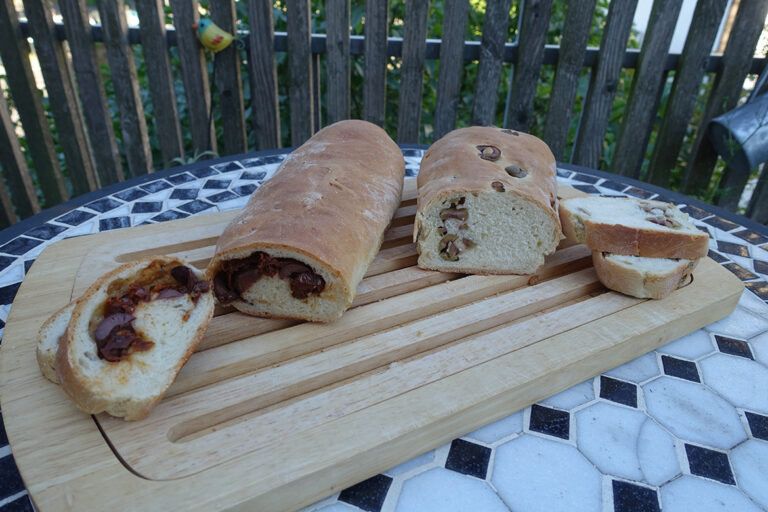 Zwei aufgeschnittene Brote auf einem Holzbrett.
