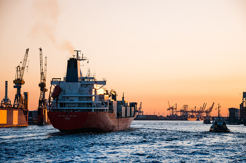 Ein Containerschiff fährt in einen Hafen ein.