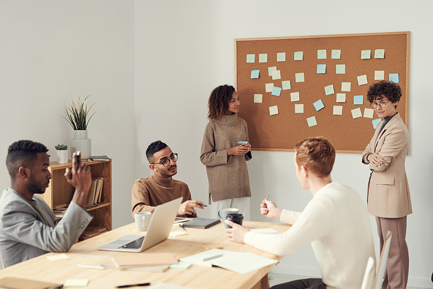 Mehrere Personen sitzen gemeinsam in einem Büro und erarbeiten an einer Pinnwand Ideen und Vorschläge.