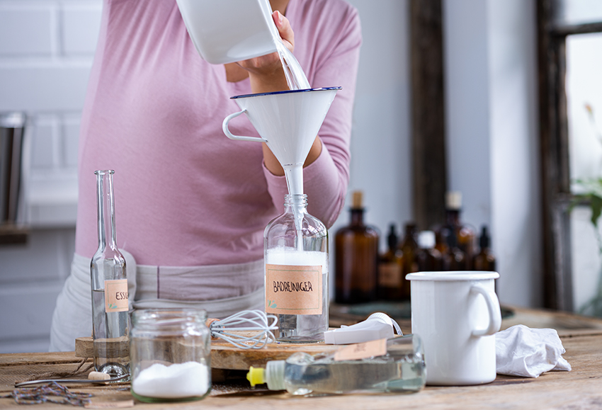 De DIY wc-reiniger wordt door een vrouw via een trechter in een fles gegoten.