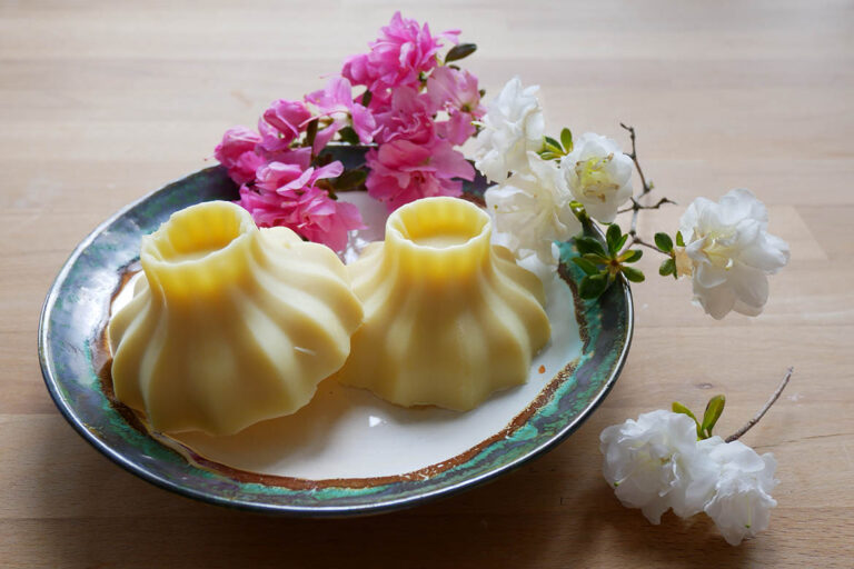 Selbstgemachte Bodybutter auf einem Teller mit Blumen dekoriert.