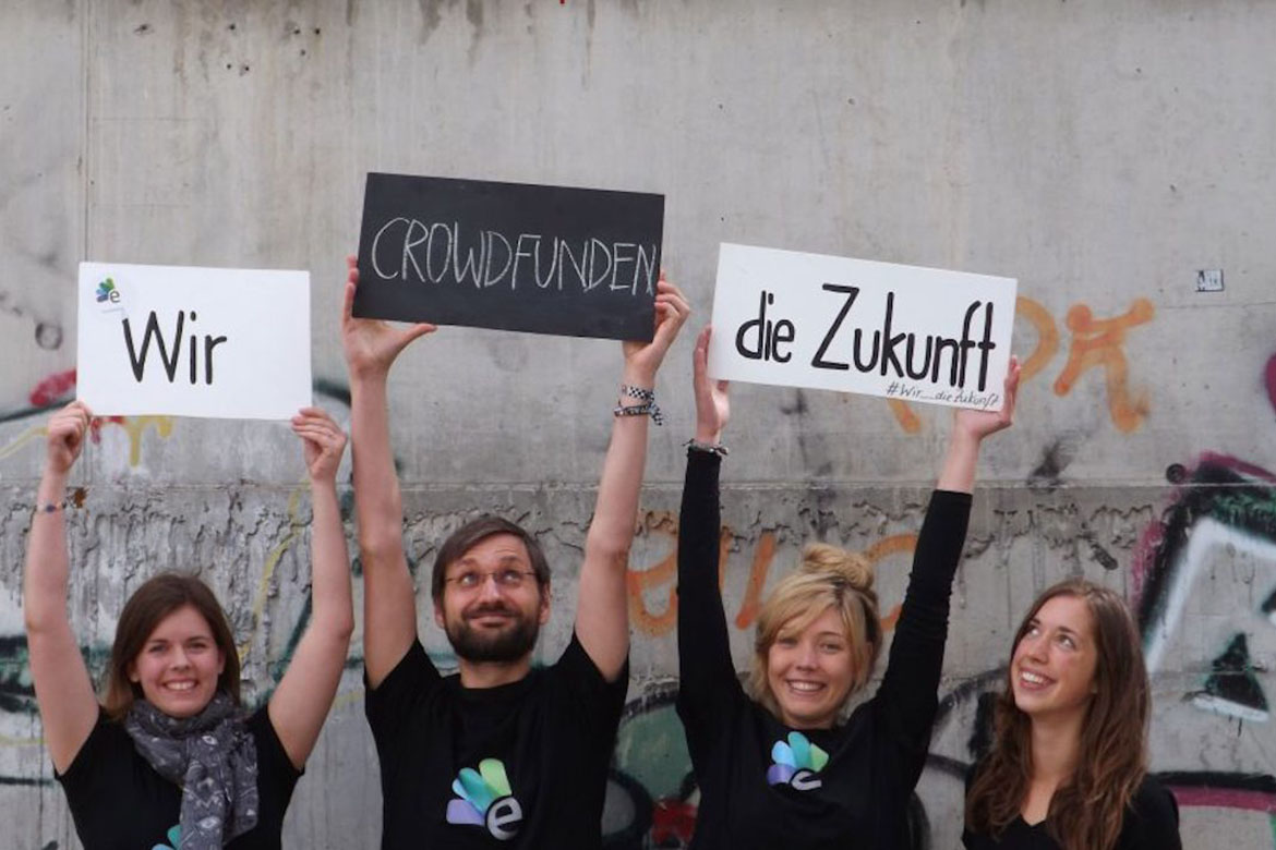 Vier Leute, drei strecken Schilder in die Höhe auf denen stehe: Wir crowdfunden die Zukunft