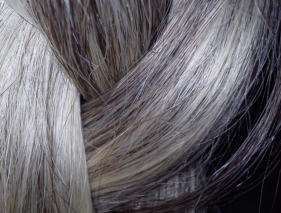 Nahaufnahme von weißen, braunen und silbrigen Haaren im Zopf.
