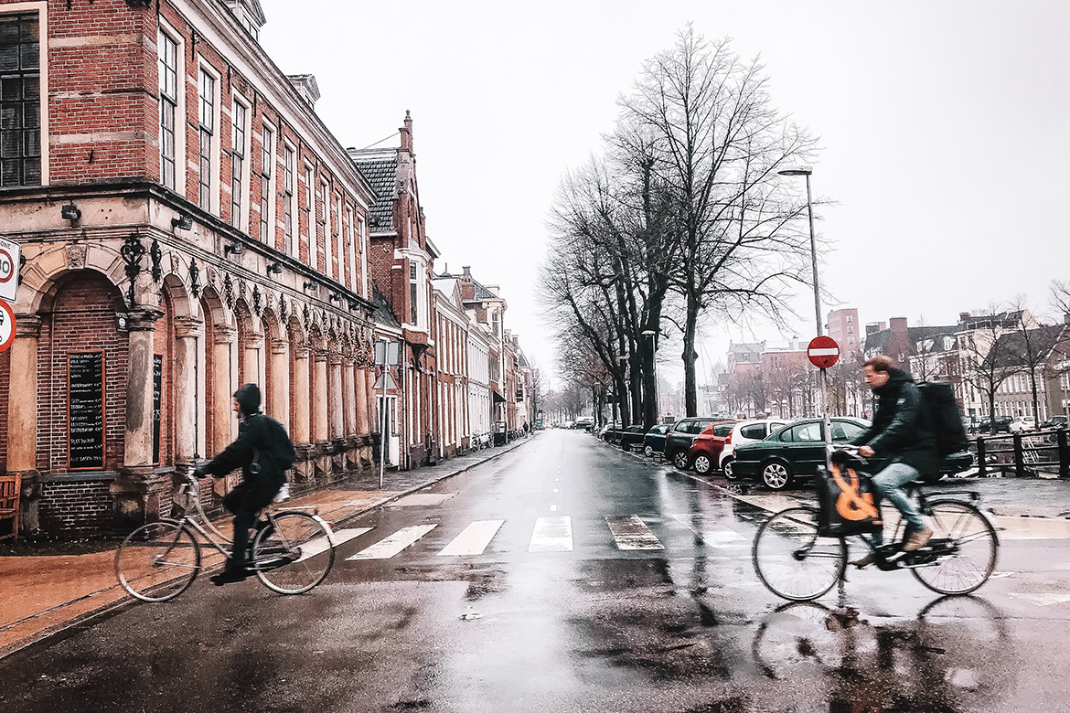 Zwei Menschen fahren auf ihren Fahrrädern auf einer nassen Straße.