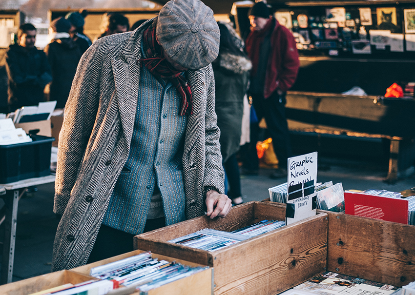 Op een rommelmarkt snuffelt een man in dozen met volgens minimalisme uitgesorteerde spullen.
