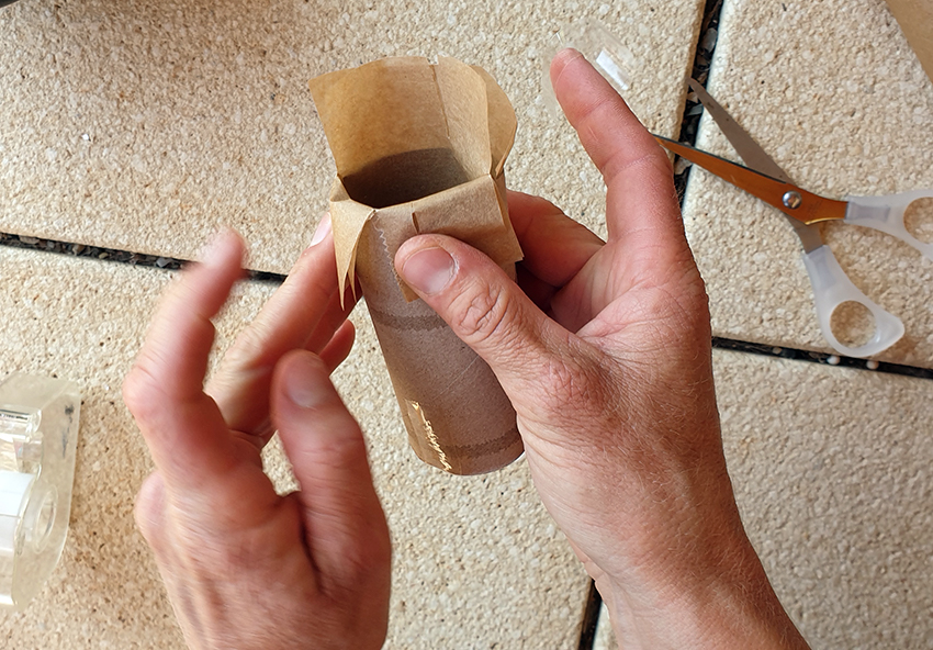 Die Form für die Kreide aus Eierschalen wird aus einer leeren Klopapierrolle und Backpapier gebastelt.