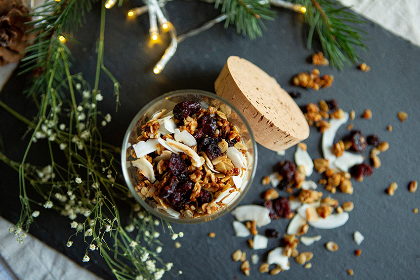 Das Granola ist in ein Glas gefüllt, welches auf einer Schieferplatte steht.