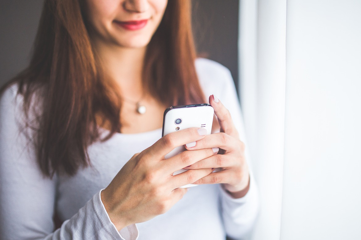 Die Frau hat ihr Handy in der Hand.