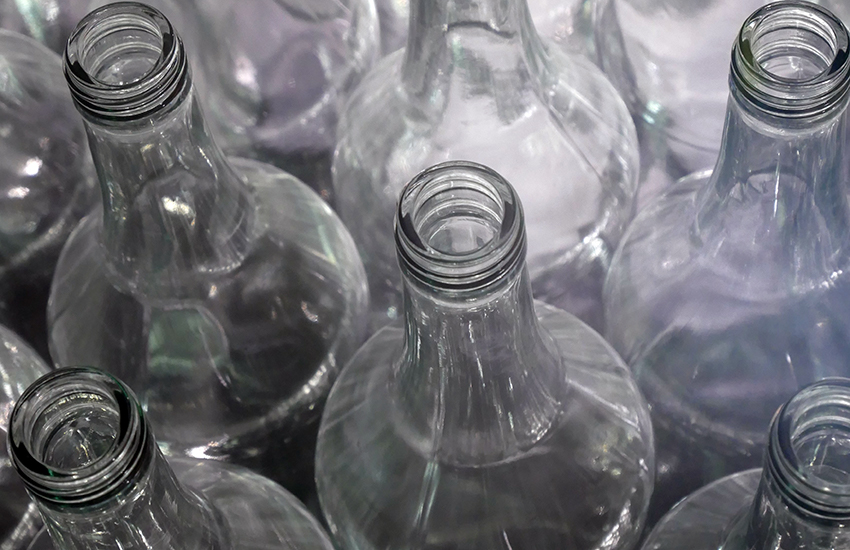 Weiße, leere Glasflaschen wurden bei der Mülltrennung sortiert und stehen nun aufgereiht zusammen.