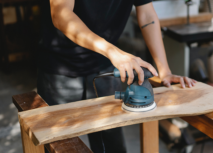 Een houten plank wordt met een machine geschuurd.