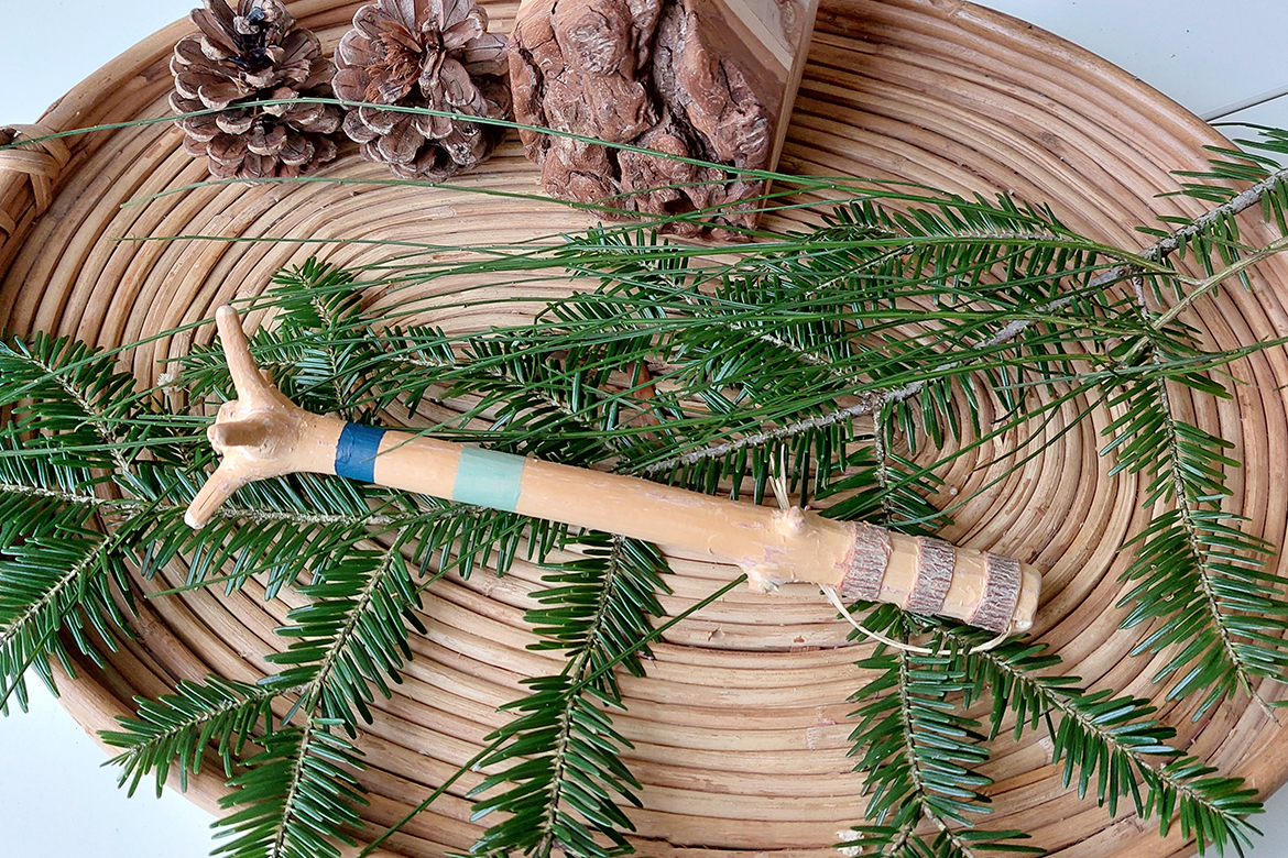 Der selbst gemachte Quirl aus einer Christbaumspitze liegt auf Tannenästen auf einem geflochtenen Tablett.
