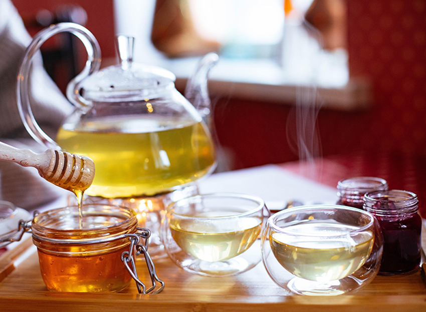 Honig wird aus einem Glas geschöpft. um in den Tee gegeben zu werden.