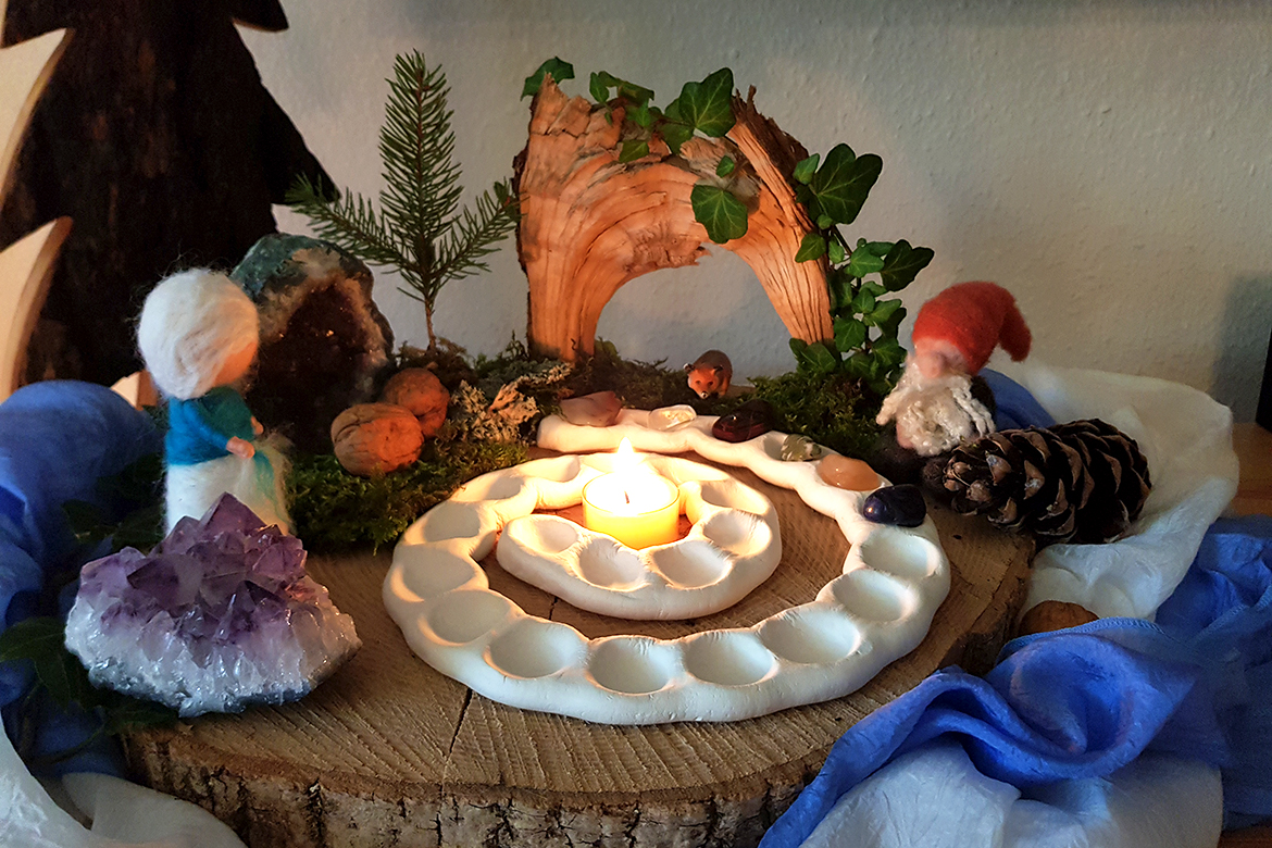 Der Jahreszeitentisch für den Winter ist unter anderem mit einer Adventsspirale, einem gefilzten Zwerg und einer Kerze geschmückt.