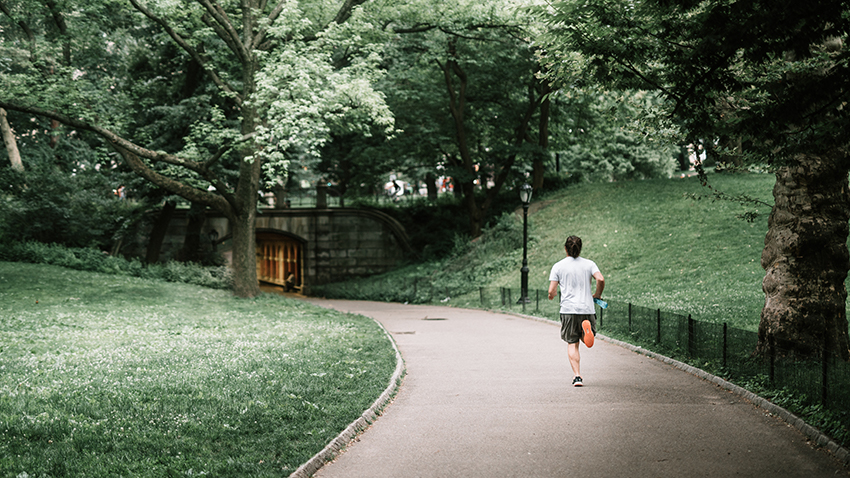 EIn Mann joggt alleine im Park.