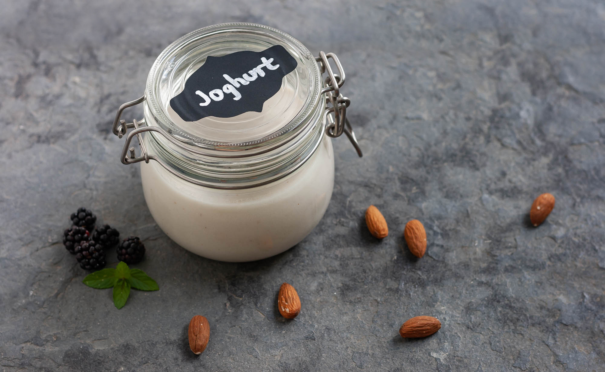 Joghurt im Bügelglas, dekoriert mit Brombeeren, Minze und Mandeln