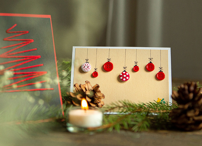 De zelfgemaakte kerstkaart is versierd met knopen die kerstballen voorstellen.