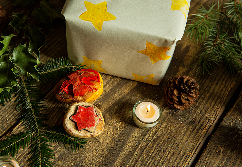 Zwei Kartoffelstempel liegen vor einem verpackten Geschenk, dass mit den Stempeln verziert wurde.