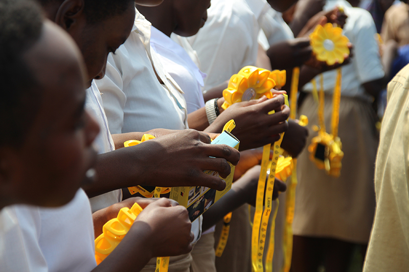 Eine Reihe Schulkinder hält die gelben Lampen in den Händen.