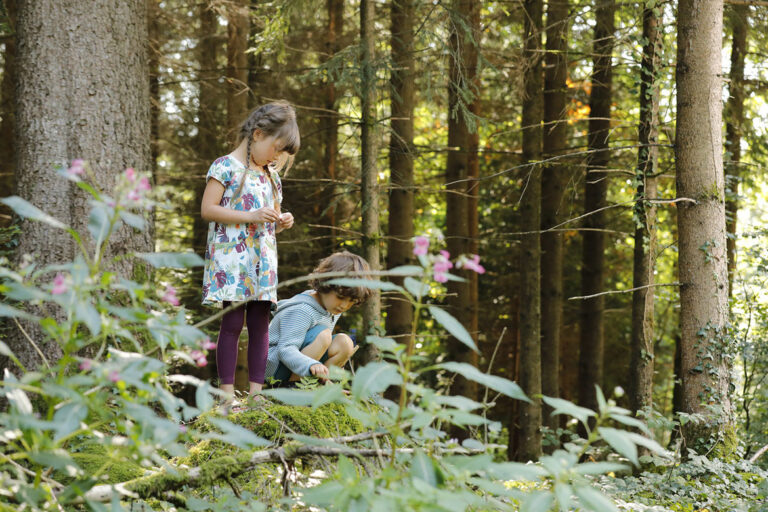 Ein Mächen und ein Junge spielen im Wald.