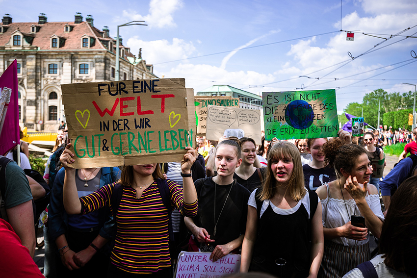Junge Menschen demonstrieren mit Plakaten gegen den Klimawandel.