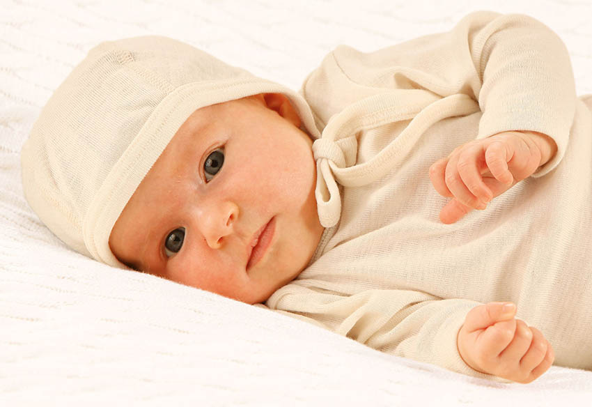 Ein Baby mit tsrampler und Mütze blickt in der Kamera