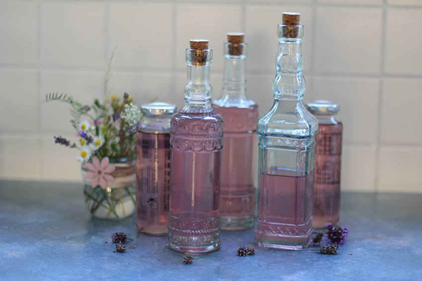 Verschiedene Flaschen mit rosa Sirup stehen beisammen.