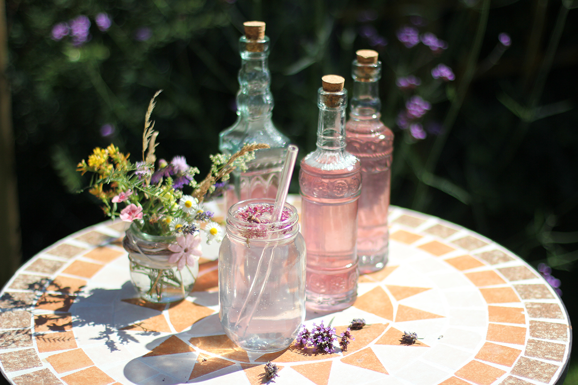Lavendel-Sirup ind Flaschen abgefüllt und in Mineralwasser eingerührt.