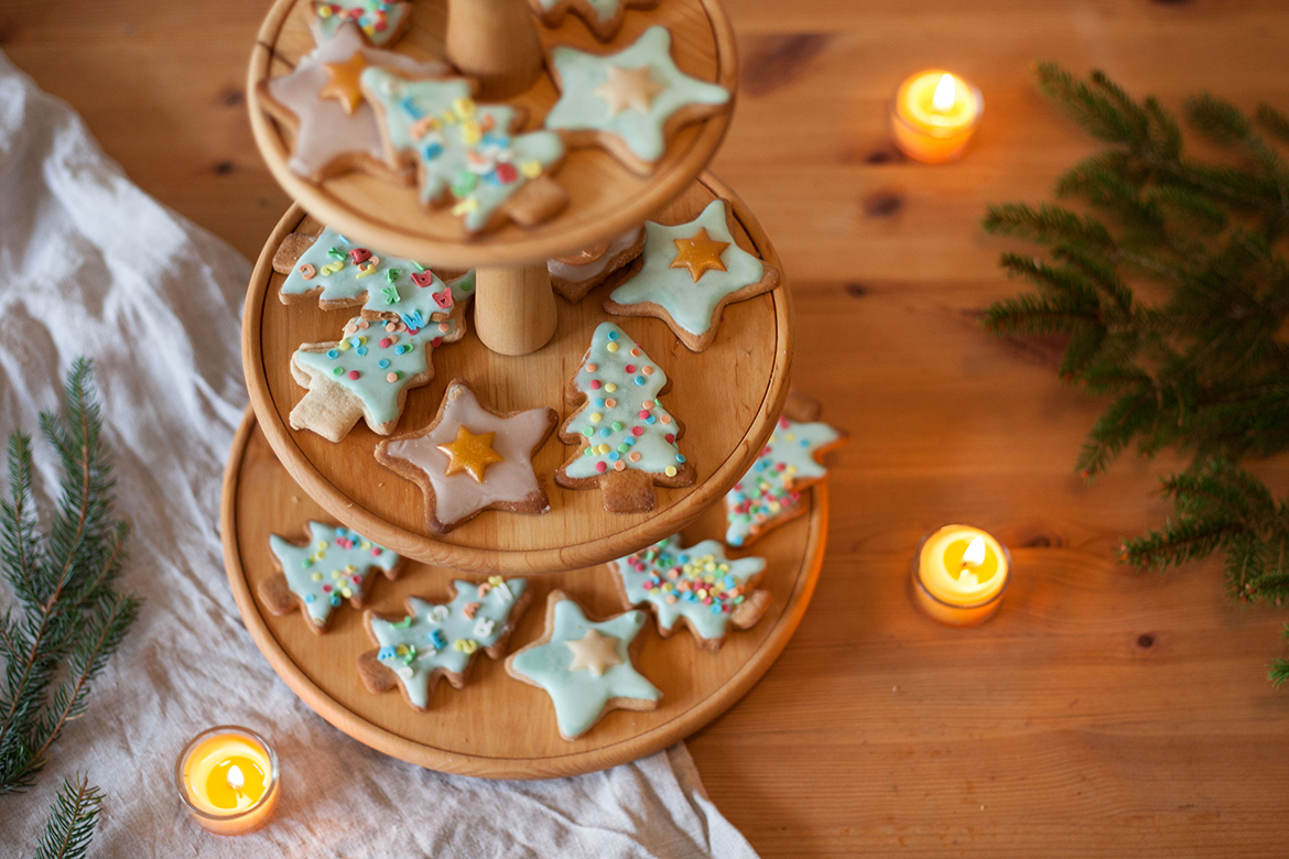 Bunte Lebkuchenkekse liegen auf einer Etagere aus Holz.