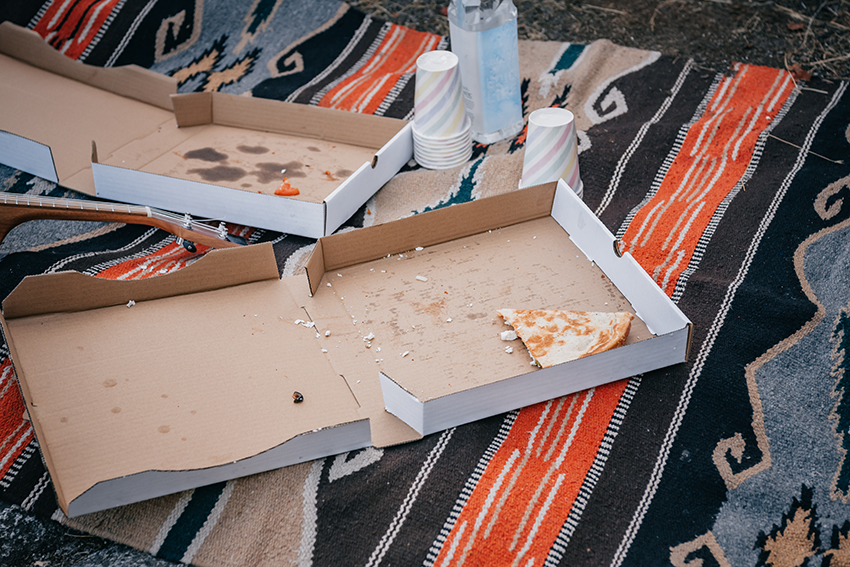Zwei leere Pizzakartons liegen auf einer Picknickdecke.