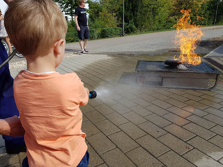 Ein Junge löscht ein Feuer mit einem Gartenschlauch.