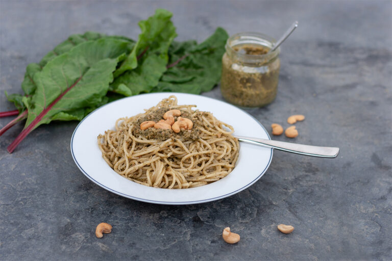 Ein Teller mit Spaghetti, die mit grünerm Pesto angemacht wurden.