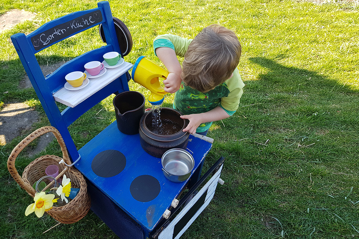 Ein kleiner Junge spielt mit der Stuhlküche.