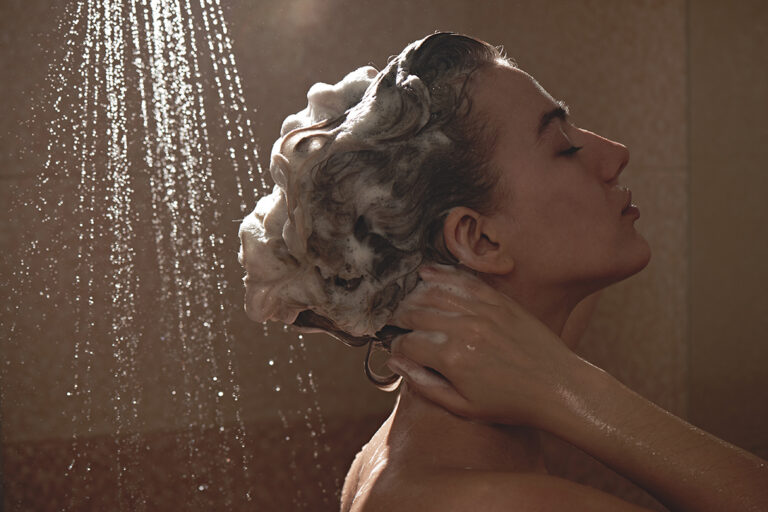 Eine Frau hat sich die Haare unter der Dusche eingeschäumt.
