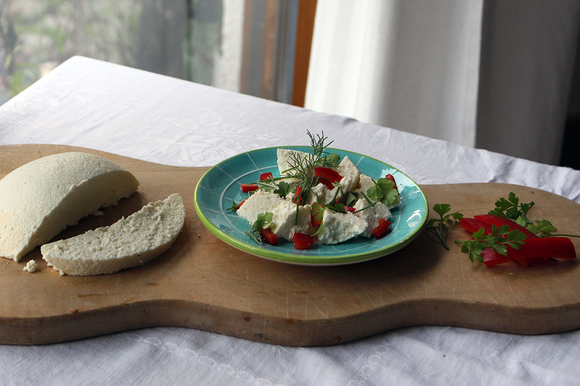 Paneer liegt auf einem Holztablett, in einer Schüssel ist der Frischkäse mit Gemüse angerichtet.