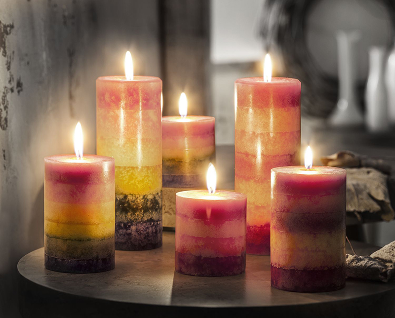 Op een tafel staan ​​zes kaarsen met verschillende afmetingen en kleuren.