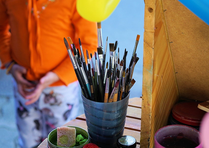 Schminkpinsel- und Schwämmchen stehen auf einem Tisch bereit, um die selbst gemachte Kinderschminke aufzutragen.